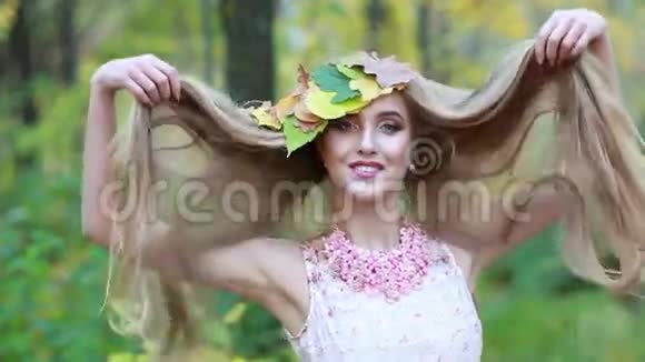 年轻的金发女孩秋天的叶子和长长的美丽的头发秋姑娘视频的预览图