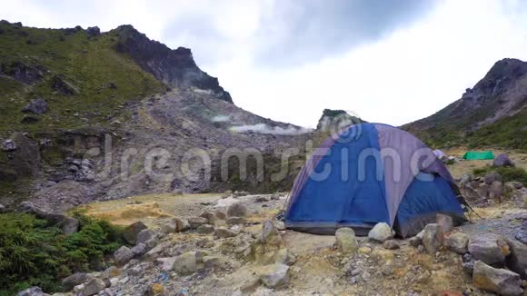 蓝色帐篷在风中战战兢兢地对抗锡巴亚克活火山上的烟幕视频的预览图