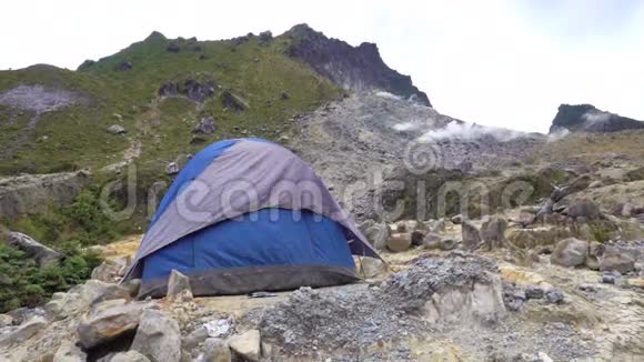 蓝色帐篷在风中战战兢兢地对抗锡巴亚克活火山上的烟幕视频的预览图