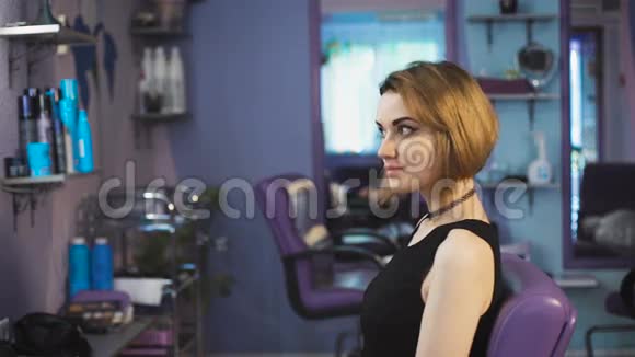 美丽的棕色头发的女人在美容院欣赏他的新发型视频的预览图