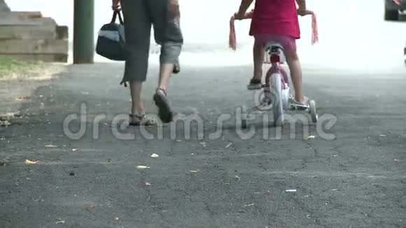 母亲骑着脚踏车边上的孩子走着视频的预览图
