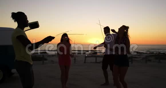 年轻的成年朋友晚上在海滩上玩火花4k视频的预览图