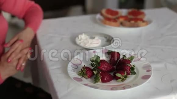 女性手拿一个新鲜多汁的草莓蘸酸奶特写镜头1920x1080视频的预览图
