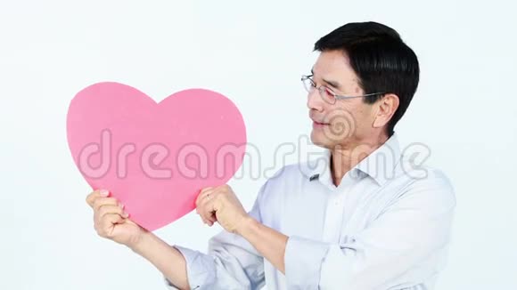 微笑的亚洲男人抱着一颗粉红色的心视频的预览图