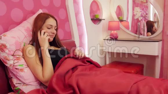 女人躺在粉红色的床上打电话说再见视频的预览图