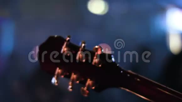 由音乐家在音乐会上演奏的吉他头架的详细镜头人们在模糊的背景下跳舞视频的预览图