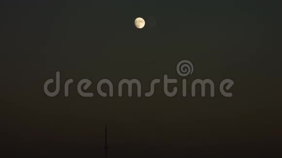 不完整的月亮在夜空与一个钢尖的建筑物在一个镜头视频的预览图