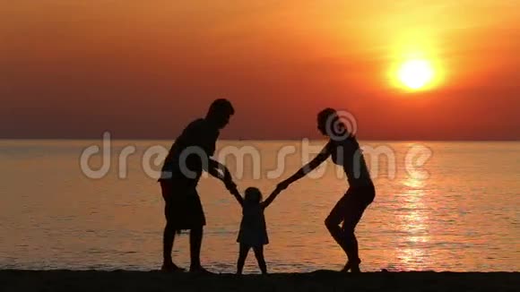 日出时在海滩上做运动的家庭剪影视频的预览图