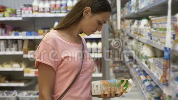 在购物中心食品杂货店冰箱里选择乳制品的女人视频的预览图