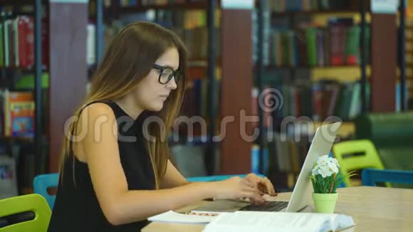 在城市图书馆用笔记本电脑工作的漂亮女学生视频的预览图