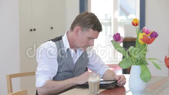一个人坐在餐厅的桌子上拿着他的平板写字视频的预览图