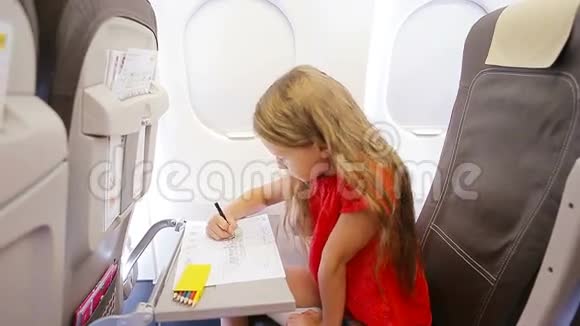 可爱的小女孩乘飞机旅行孩子们坐在飞机窗前画着彩色铅笔视频的预览图