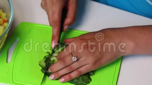 带有蔬菜和蛋黄酱的俄罗斯肉沙拉女人把切好的黄瓜放进一个盛有沙拉的容器里视频的预览图