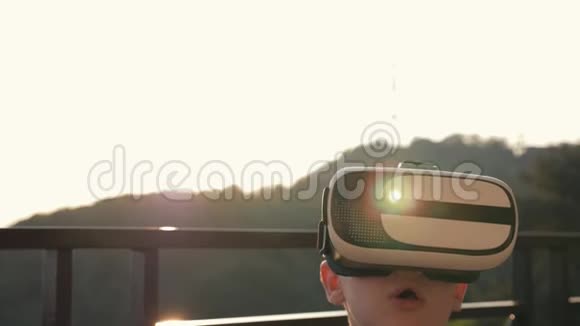 这个男孩正在电脑上玩虚拟现实眼镜在日落时现代概念视频的预览图