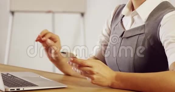 严肃的女商人用她的笔记本电脑和智能手机视频的预览图