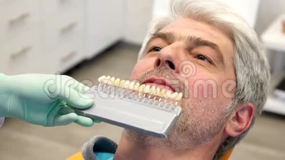 一位牙医检查一位年轻人牙齿颜色的阴影视频的预览图