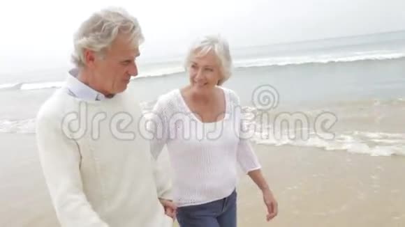 年长夫妇沿着米斯蒂海滩散步视频的预览图