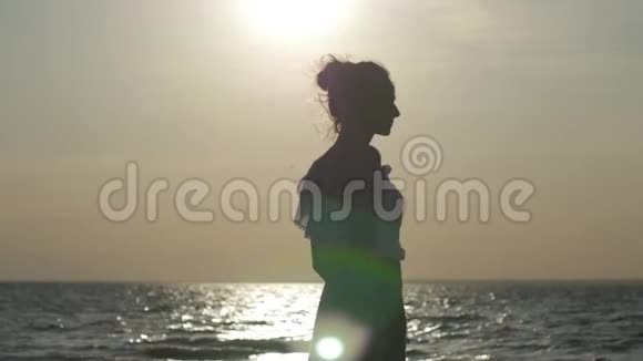 日落时分一个女人在海滩上跳舞的剪影空中飞裙视频的预览图