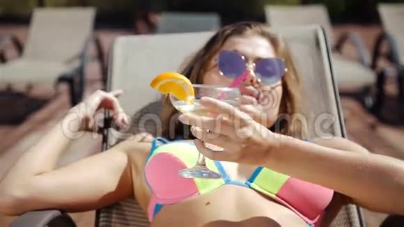 快乐的女人在游泳池边喝异国情调的鸡尾酒20岁1080p慢速运动视频的预览图