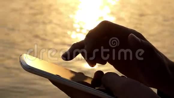手使用触摸电话在日落附近的水视频的预览图