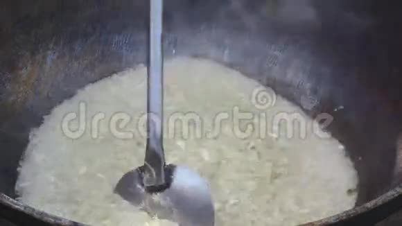 黄油煎锅中的洋葱圈与大勺混合视频的预览图