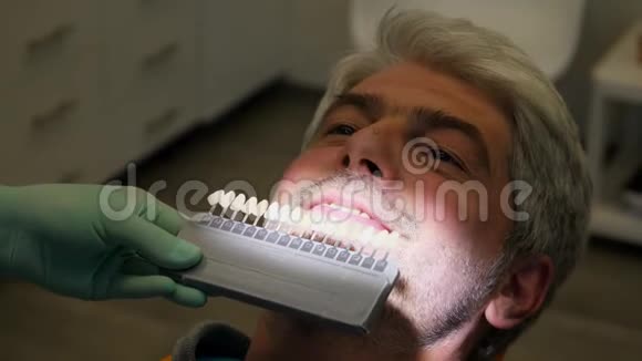 一位牙医检查一位年轻人牙齿颜色的阴影视频的预览图