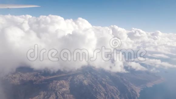 在飞往美国拉斯维加斯的商业航班上在白云之上飞行下面是山脉与翼视频的预览图