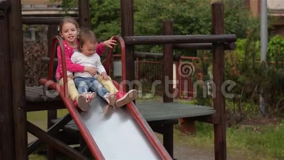 两个可爱的小女孩在操场上滑滑梯玩得很开心视频的预览图