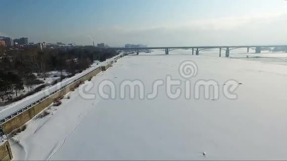 冬天飞过冰冻的河流河上的桥路基视频的预览图