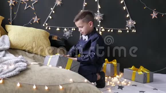 男孩在花环的背景下展开圣诞礼物视频的预览图