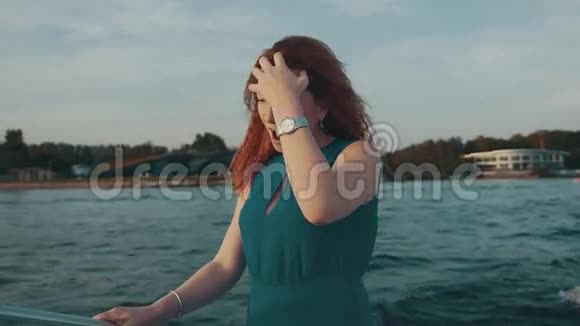快乐的红发女孩穿着绿松石裙在摩托艇上跳舞去摇头发乐趣视频的预览图