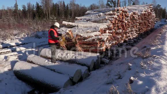冬天伐木工人在一堆原木附近扔绳子视频的预览图