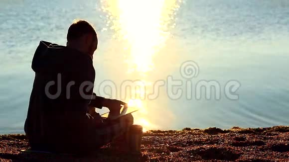 一个拿着石碑的人坐在海边的沙砾滩上视频的预览图