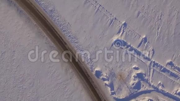 鸟瞰雪域和道路越野车在冬天的道路上行驶穿过雪地汽车的鸟瞰图视频的预览图