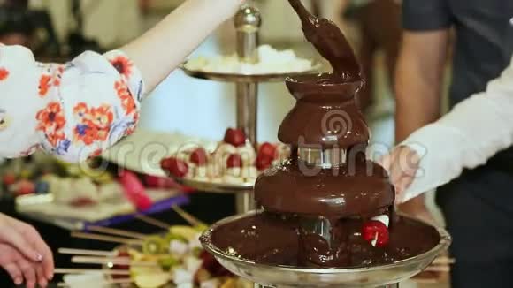 人们把草莓浸在巧克力喷泉里视频的预览图