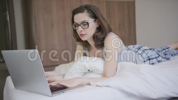 穿睡衣的女人用笔记本电脑视频的预览图