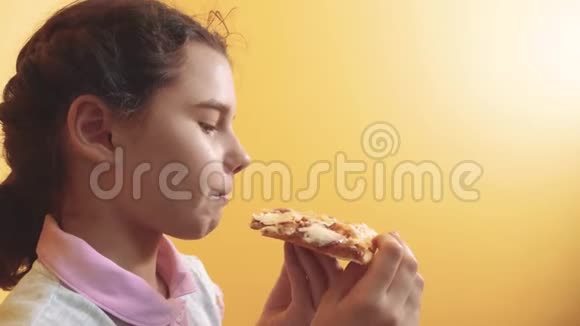 快乐的小女孩吃一片披萨的概念十几岁的孩子饿了吃一片比萨饼的生活方式慢动作视频的预览图