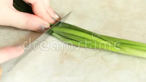 雌性的手在小块上切一个绿色的洋葱视频的预览图