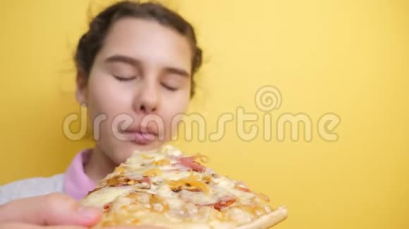 快乐的小女孩吃一片披萨的概念十几岁的孩子饿了吃一片披萨慢动作视频披萨饼视频的预览图