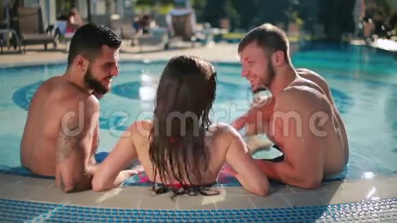 两个迷人的男人和年轻漂亮的女人在游泳池里放松视频的预览图