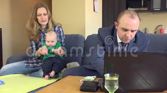 父亲算家庭预算妈妈带着婴儿在沙发上玩耍视频的预览图