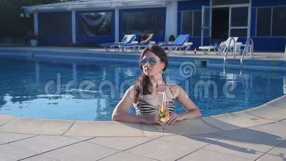 穿比基尼的性感单身女人在游泳池里喝鸡尾酒视频的预览图