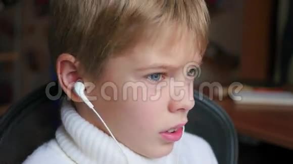 孩子在耳机里听智能手机上的音乐在家里跳着头视频的预览图
