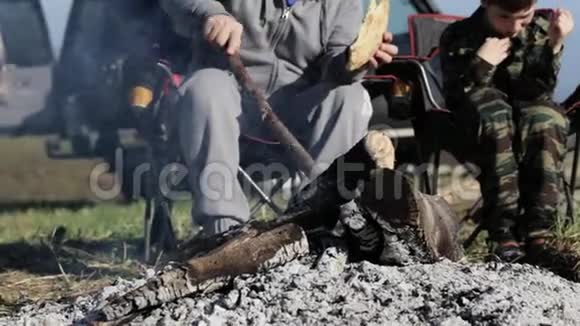 父子俩在篝火旁吃烤面包视频的预览图