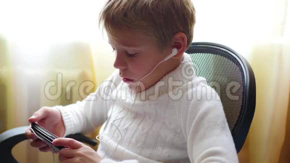 孩子在耳机里听智能手机上的音乐在家里跳着头视频的预览图