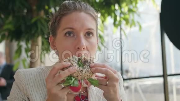 一位年轻的女士在咖啡馆里吃三明治视频的预览图