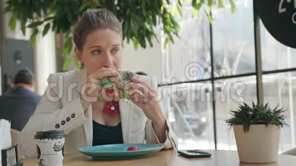 一位年轻的女士在咖啡馆里吃三明治视频的预览图