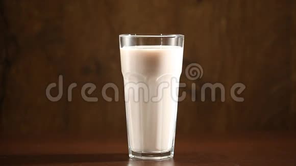年轻人的手从桌子上拿出一杯牛奶放在棕色的背景上视频的预览图