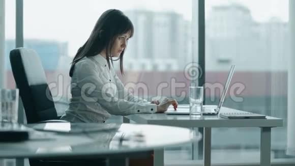年轻的商业女性在现代办公室的笔记本电脑上工作她停下来是因为背疼视频的预览图
