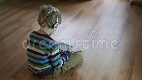 男孩用平板电脑通过耳机听音乐视频的预览图